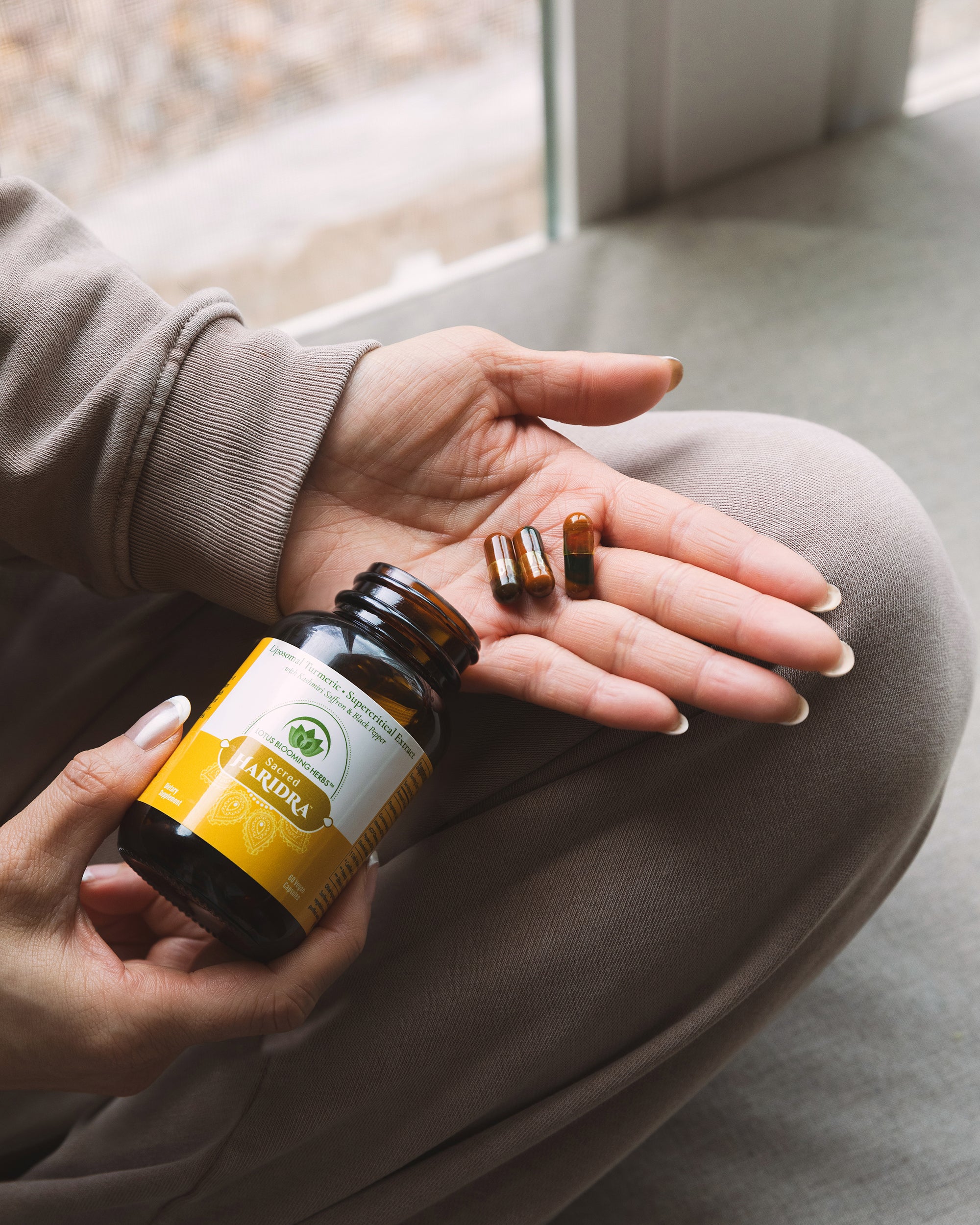 Person holding a bottle of supplements with capsules in their hand.